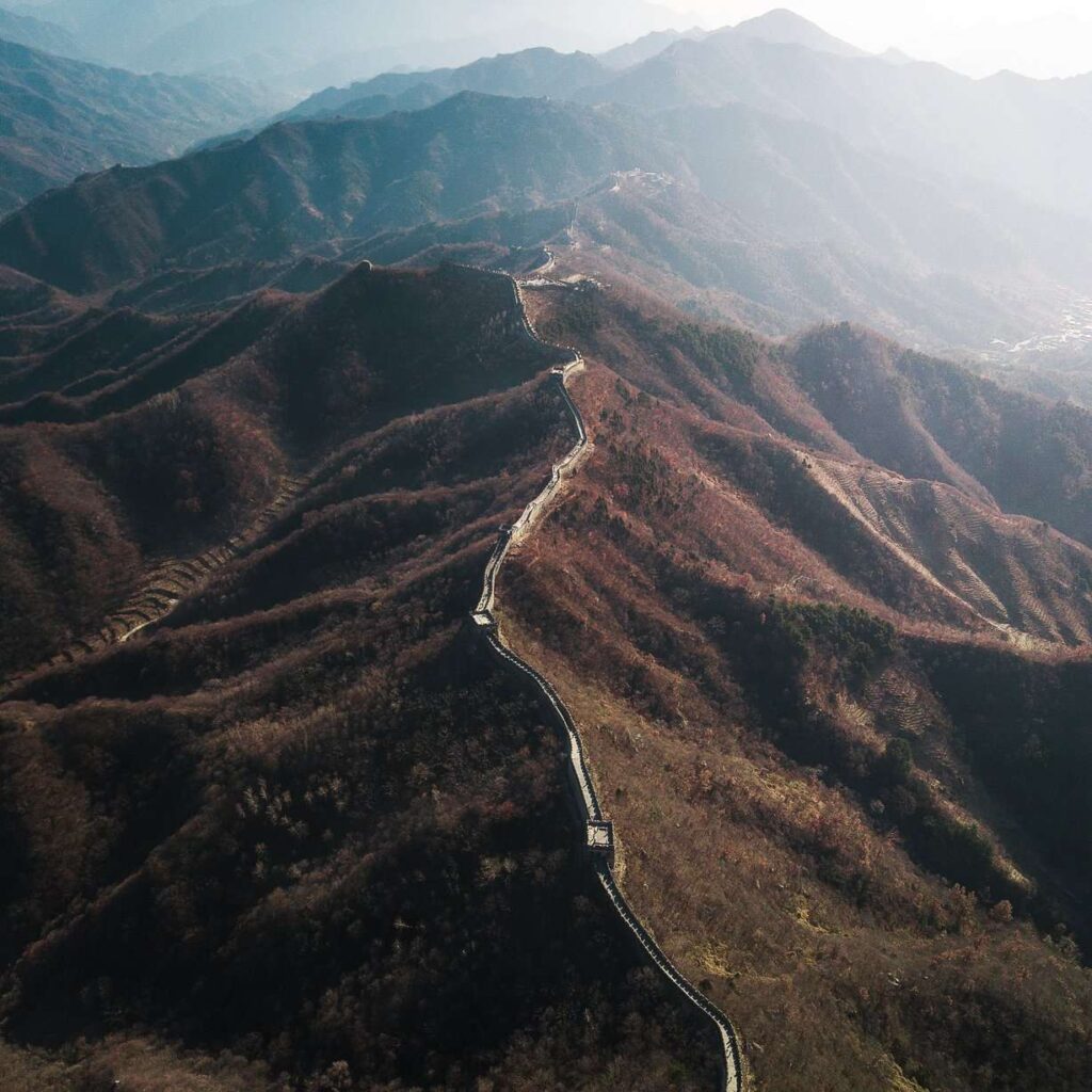 aerial drone photography of the great wall of china with sunlight shining on the side