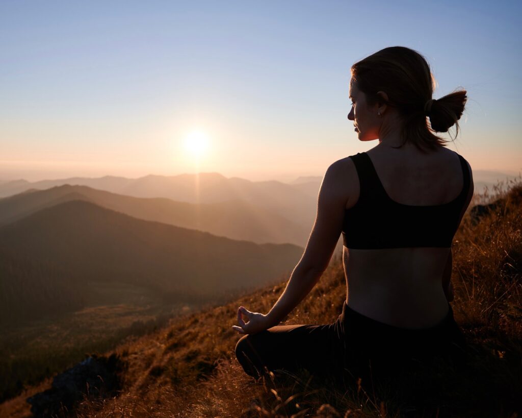 woman is meditating in lotus pose in mountains.